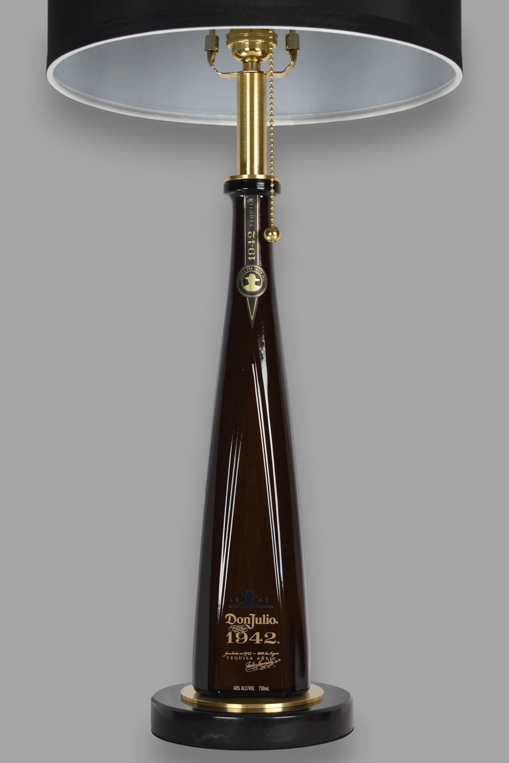 Liquor bottle lamp made from a reclaimed Don Julio 1942 Tequila bottle, front view, on a gray background