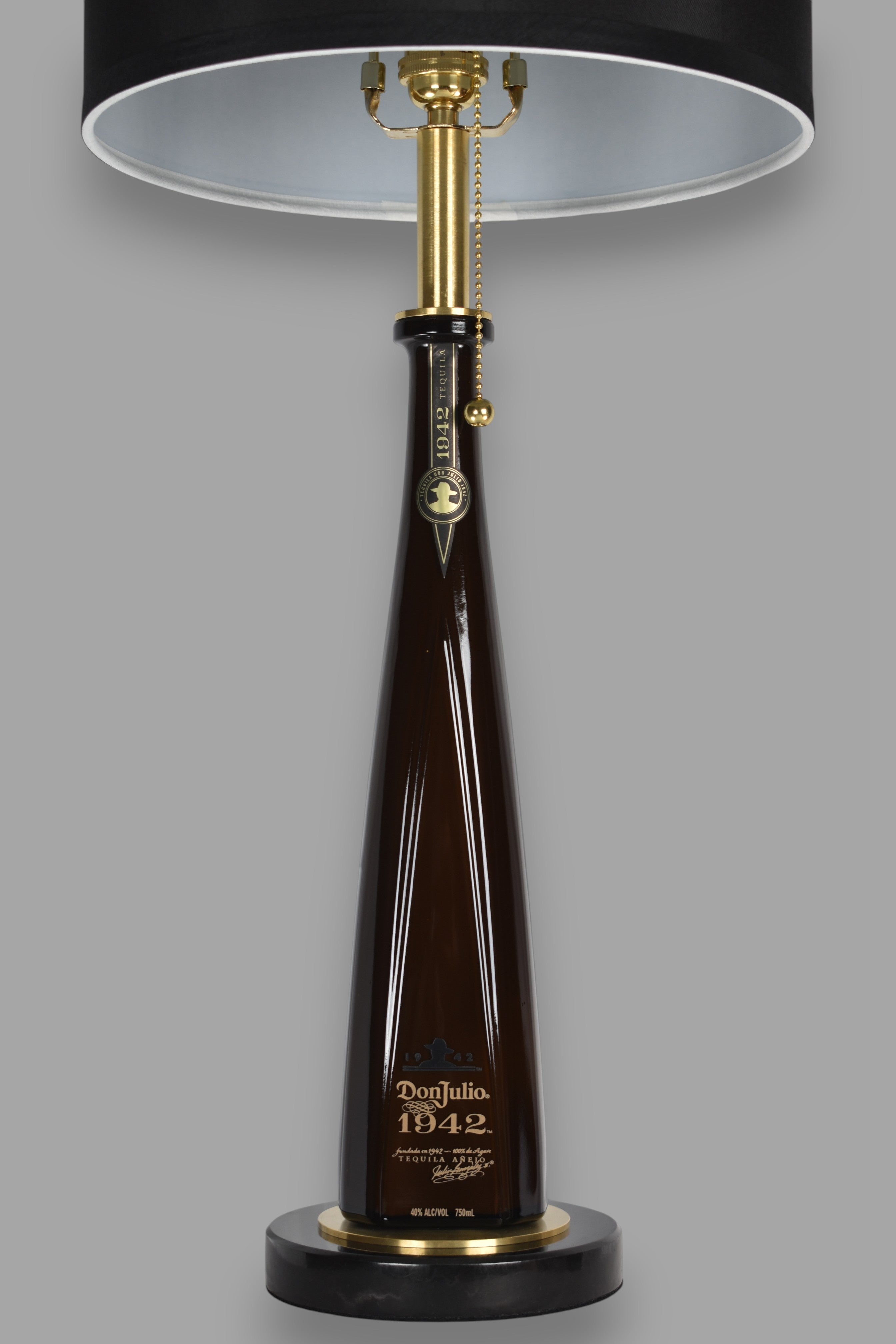 Liquor bottle lamp made from a reclaimed Don Julio 1942 Tequila bottle, front view, on a gray background