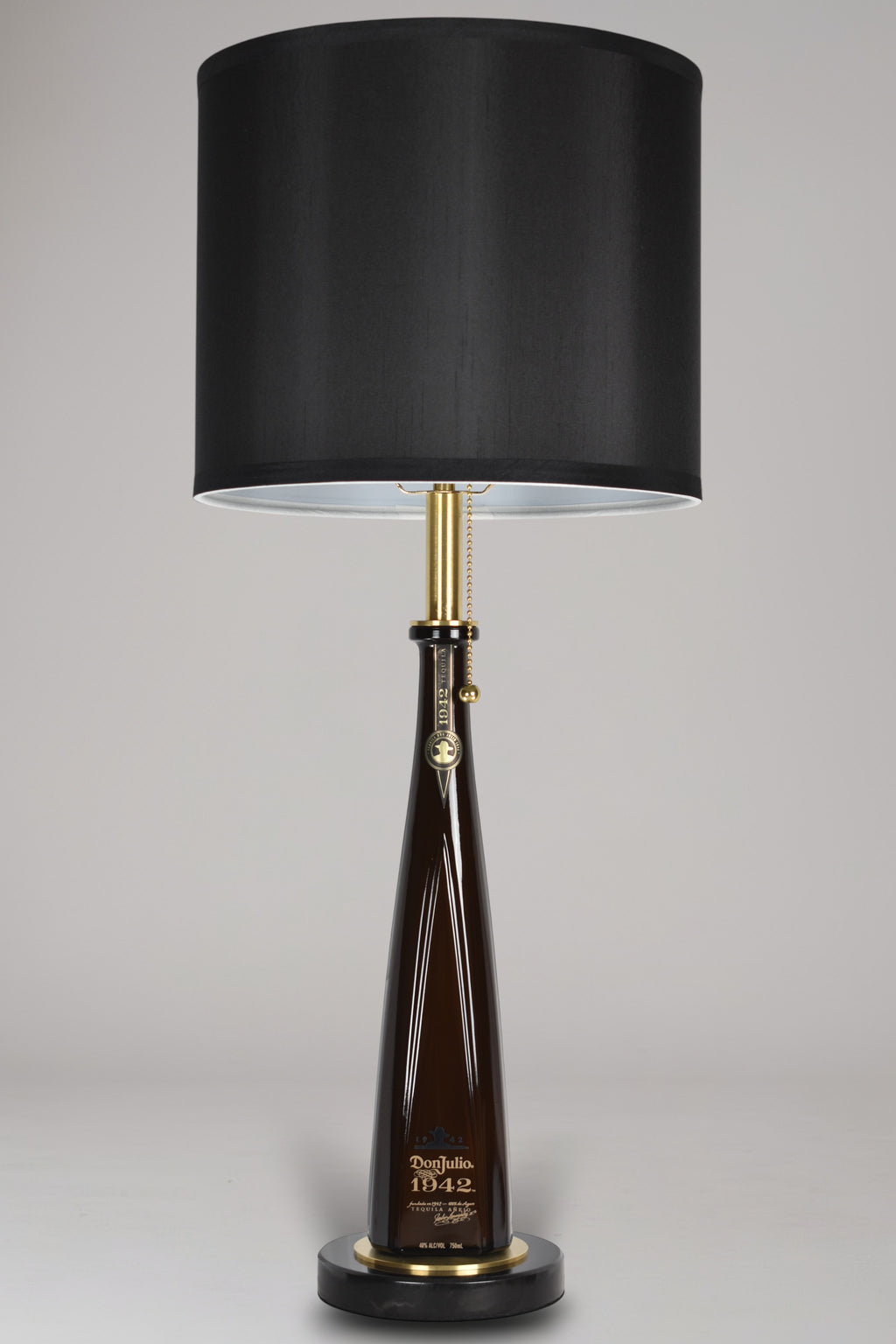 Liquor bottle lamp made from a reclaimed Don Julio 1942 Tequila bottle, full view, light off, on a gray background
