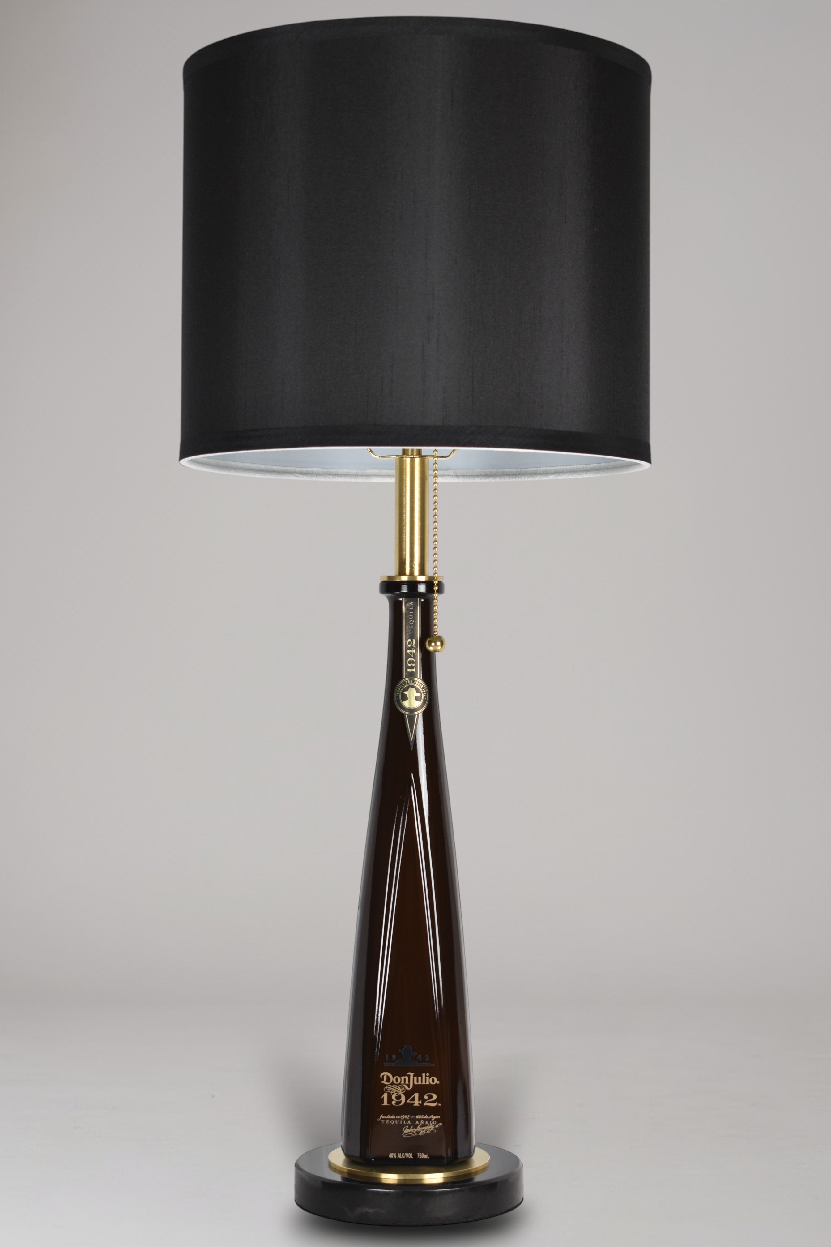 Liquor bottle lamp made from a reclaimed Don Julio 1942 Tequila bottle, full view, light off, on a gray background