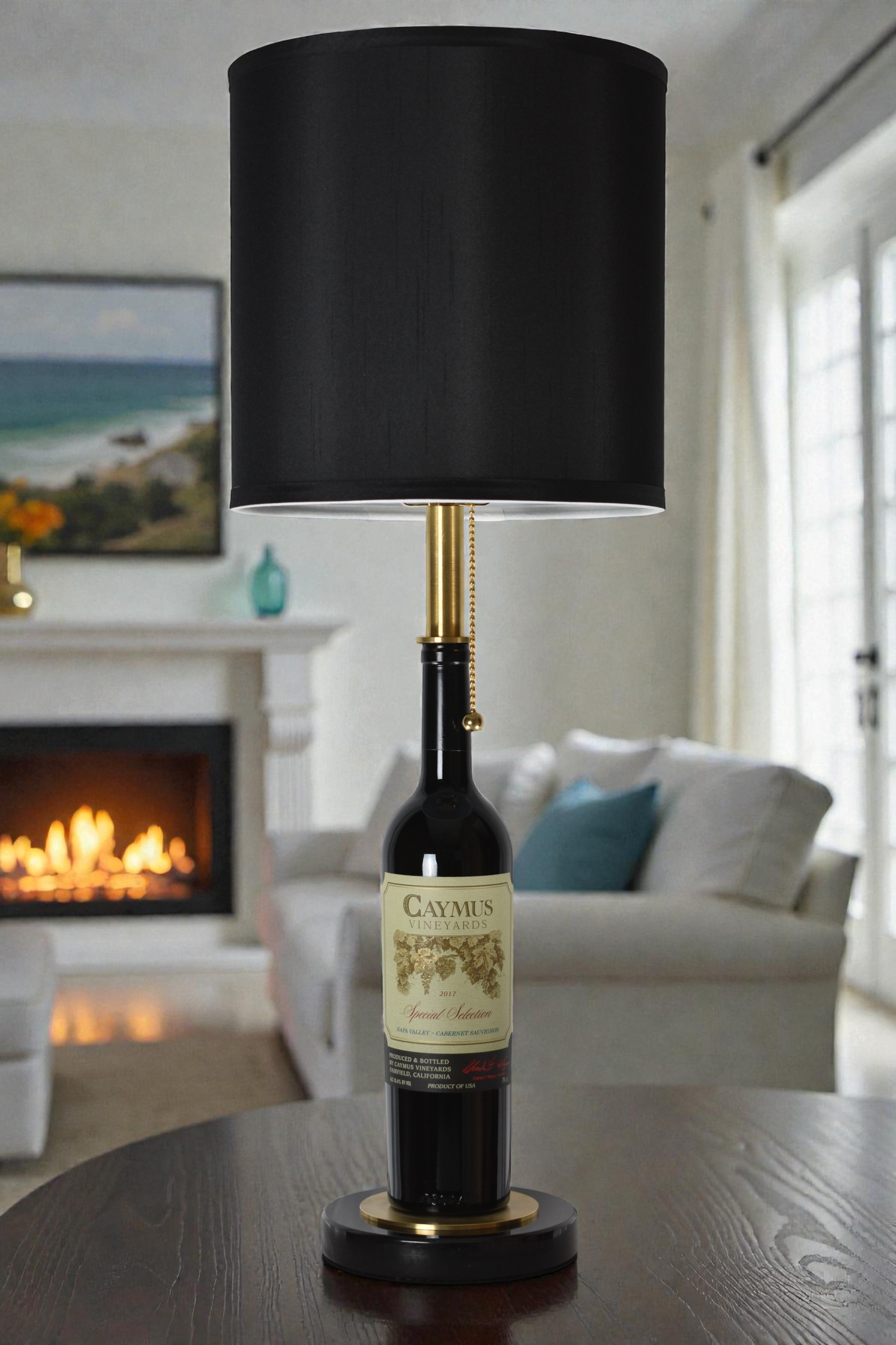 Wine bottle lamp made from a reclaimed 2017 Caymus Cabernet Sauvignon bottle, full view, light off, in a cozy living room
