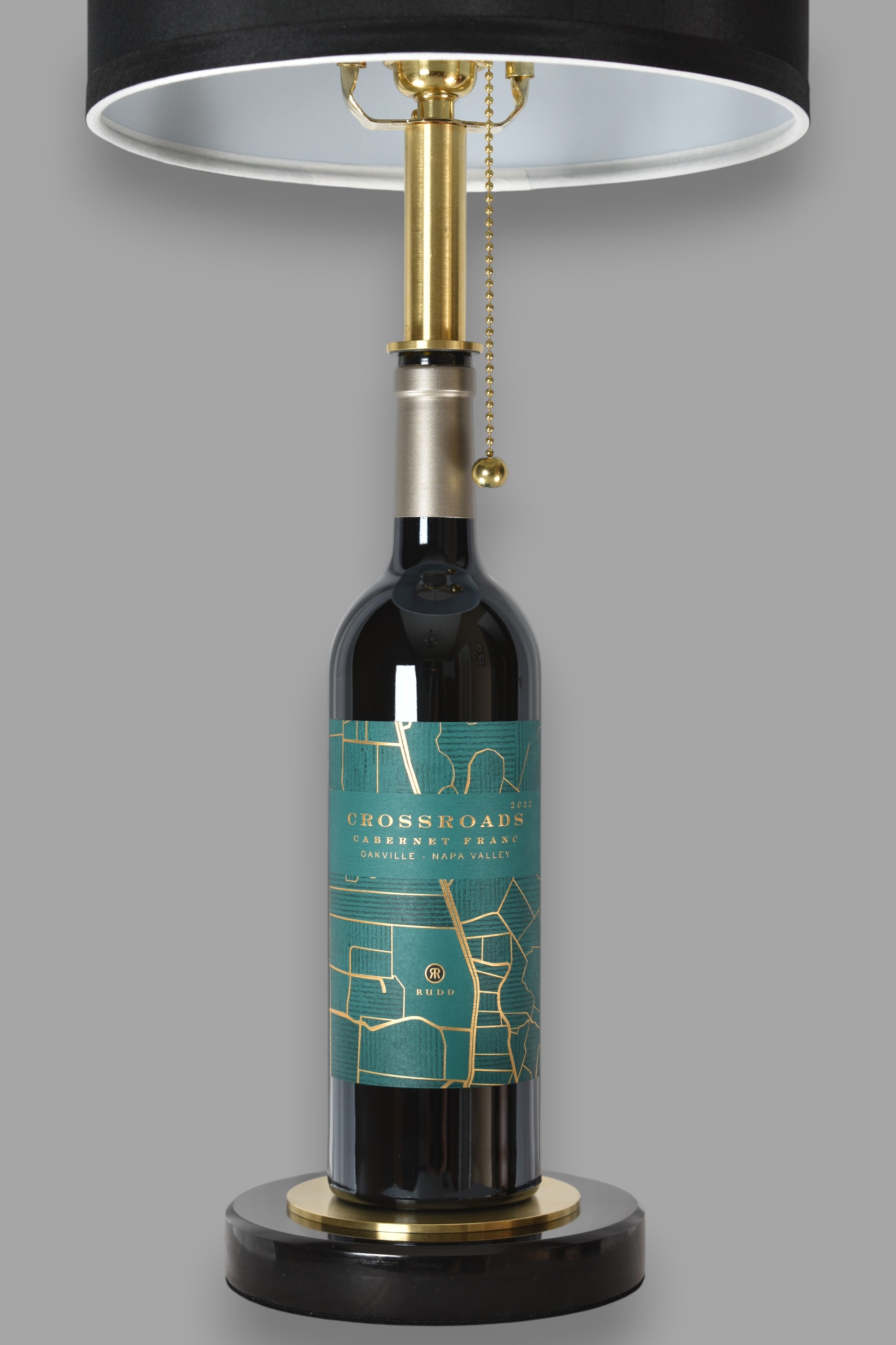 Wine bottle lamp made from a reclaimed 2022 Crossroads Cabernet Franc bottle, front view, on a gray background