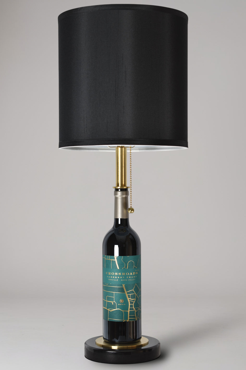 Wine bottle lamp made from a reclaimed 2022 Crossroads Cabernet Franc bottle, full view, light off, on a gray background
