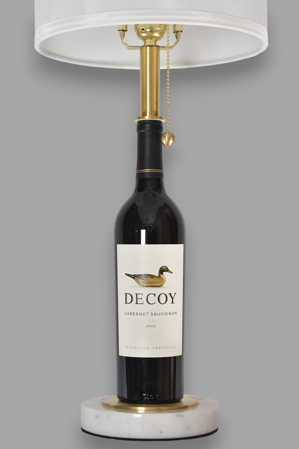 Wine bottle lamp made from a reclaimed 2022 Decoy Cabernet Sauvignon bottle, front view, on a gray background