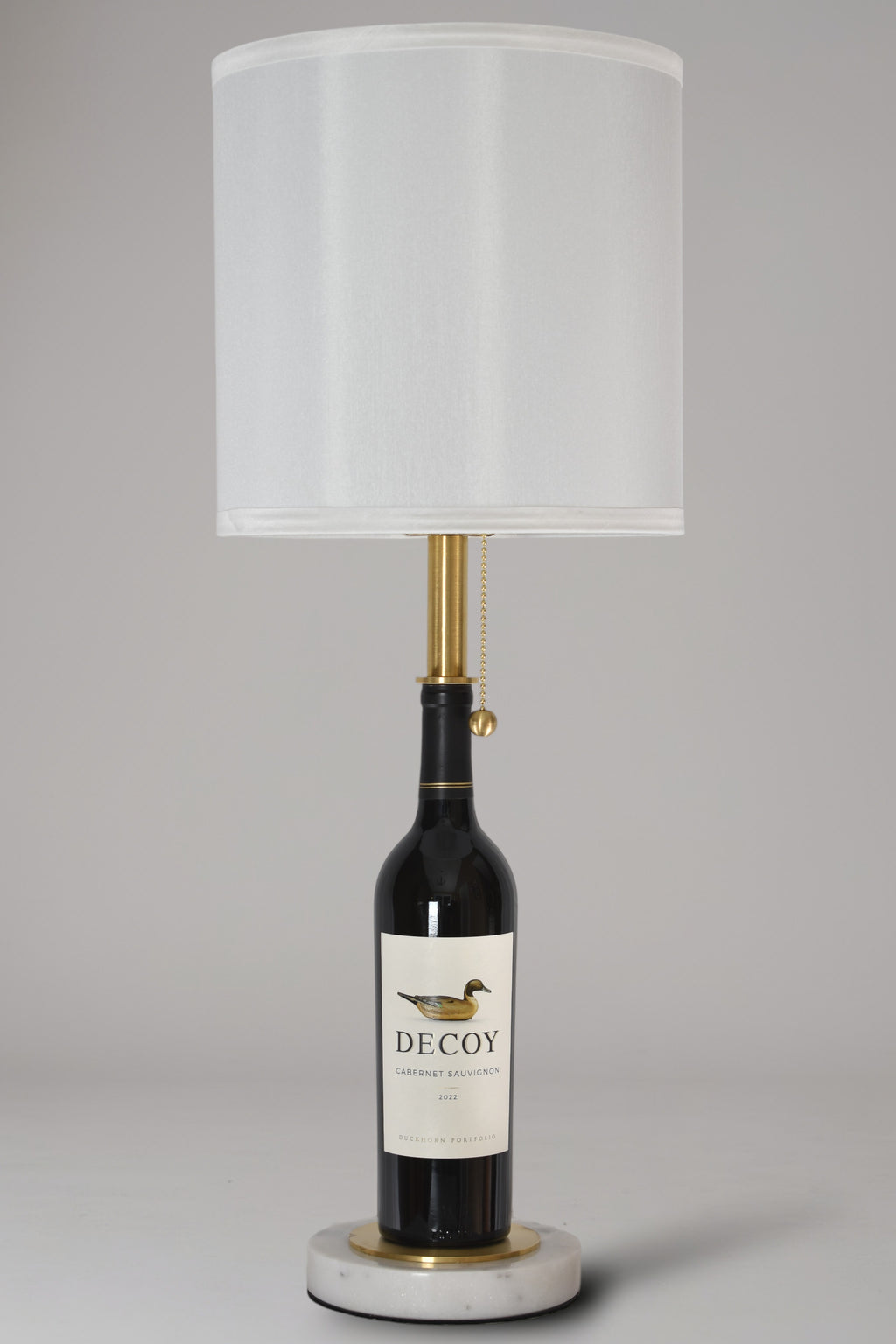 Wine bottle lamp made from a reclaimed 2022 Decoy Cabernet Sauvignon bottle, full view, light off, on a gray background