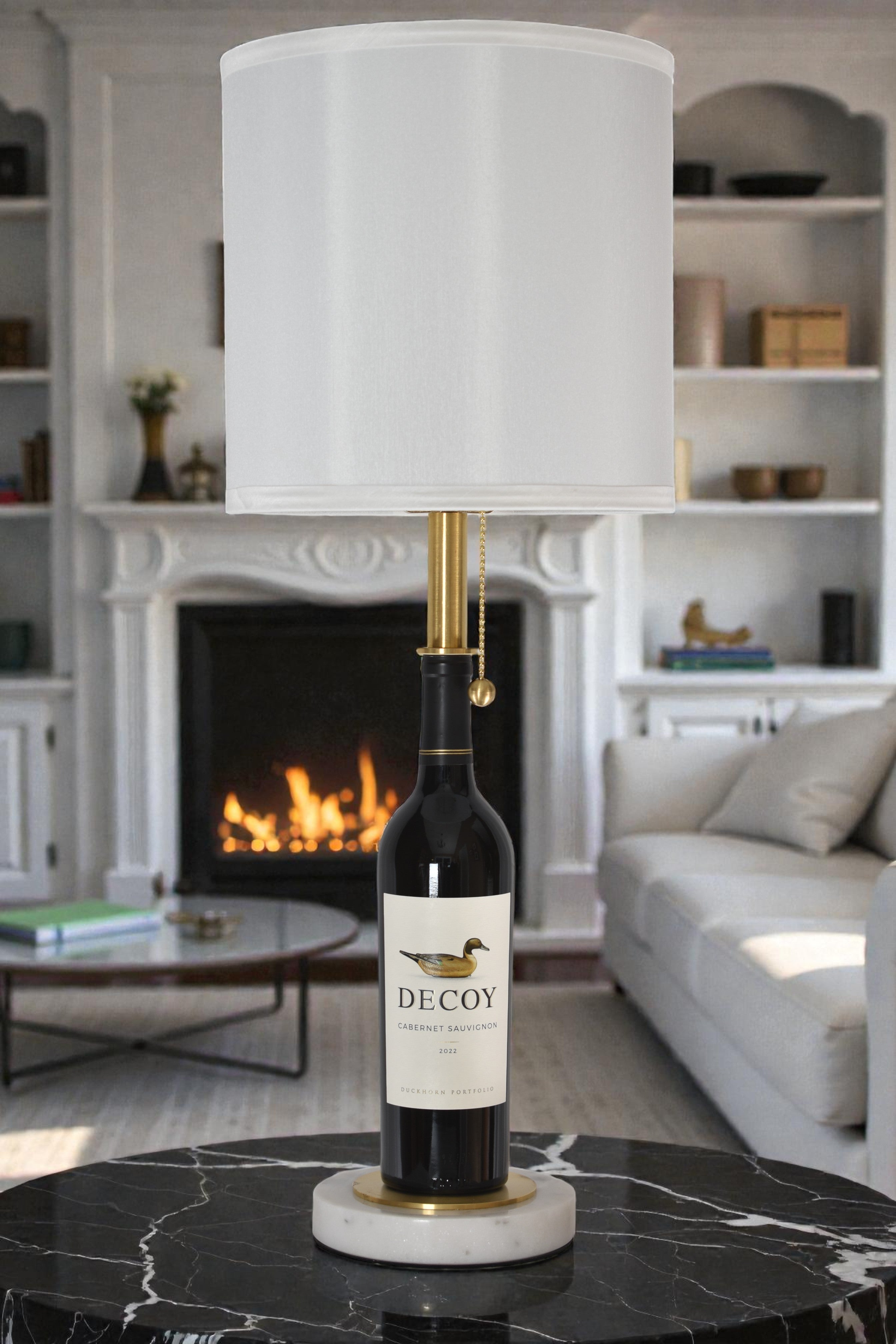 Wine bottle lamp made from a reclaimed 2022 Decoy Cabernet Sauvignon bottle, full view, light off, in a cozy living room