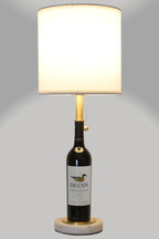 Wine bottle lamp made from a reclaimed 2022 Decoy Cabernet Sauvignon bottle, full view, light on, on a gray background