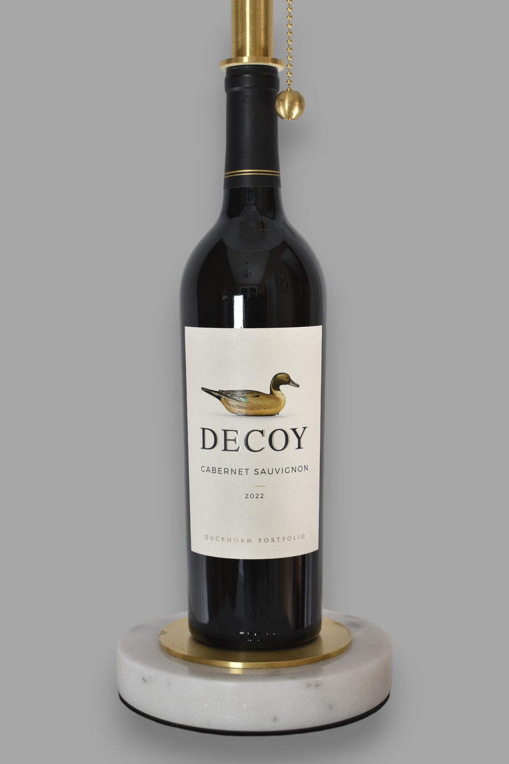 Wine bottle lamp made from a reclaimed 2022 Decoy Cabernet Sauvignon bottle, close-up view, on a gray background