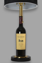 Wine bottle lamp made from a reclaimed 2022 Duckhorn Merlot bottle, front view, on a gray background