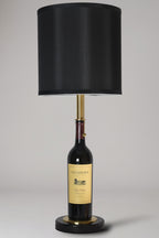Wine bottle lamp made from a reclaimed 2022 Duckhorn Merlot bottle, full view, light off, on a gray background