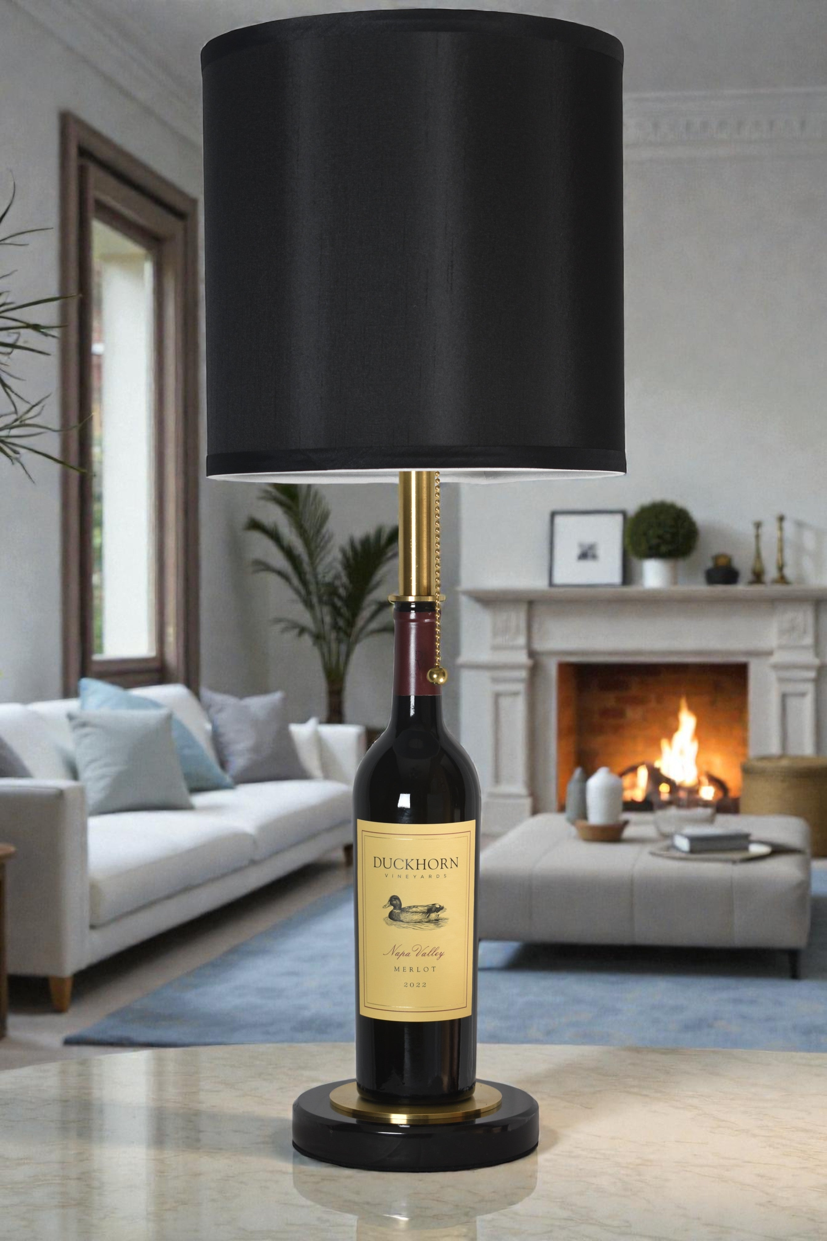 Wine bottle lamp made from a reclaimed 2022 Duckhorn Merlot bottle, full view, light off, in a cozy living room