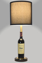 Wine bottle lamp made from a reclaimed 2022 Duckhorn Merlot bottle, full view, light on, on a gray background