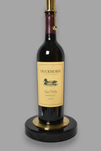 Wine bottle lamp made from a reclaimed 2022 Duckhorn Merlot bottle, close-up view, on a gray background