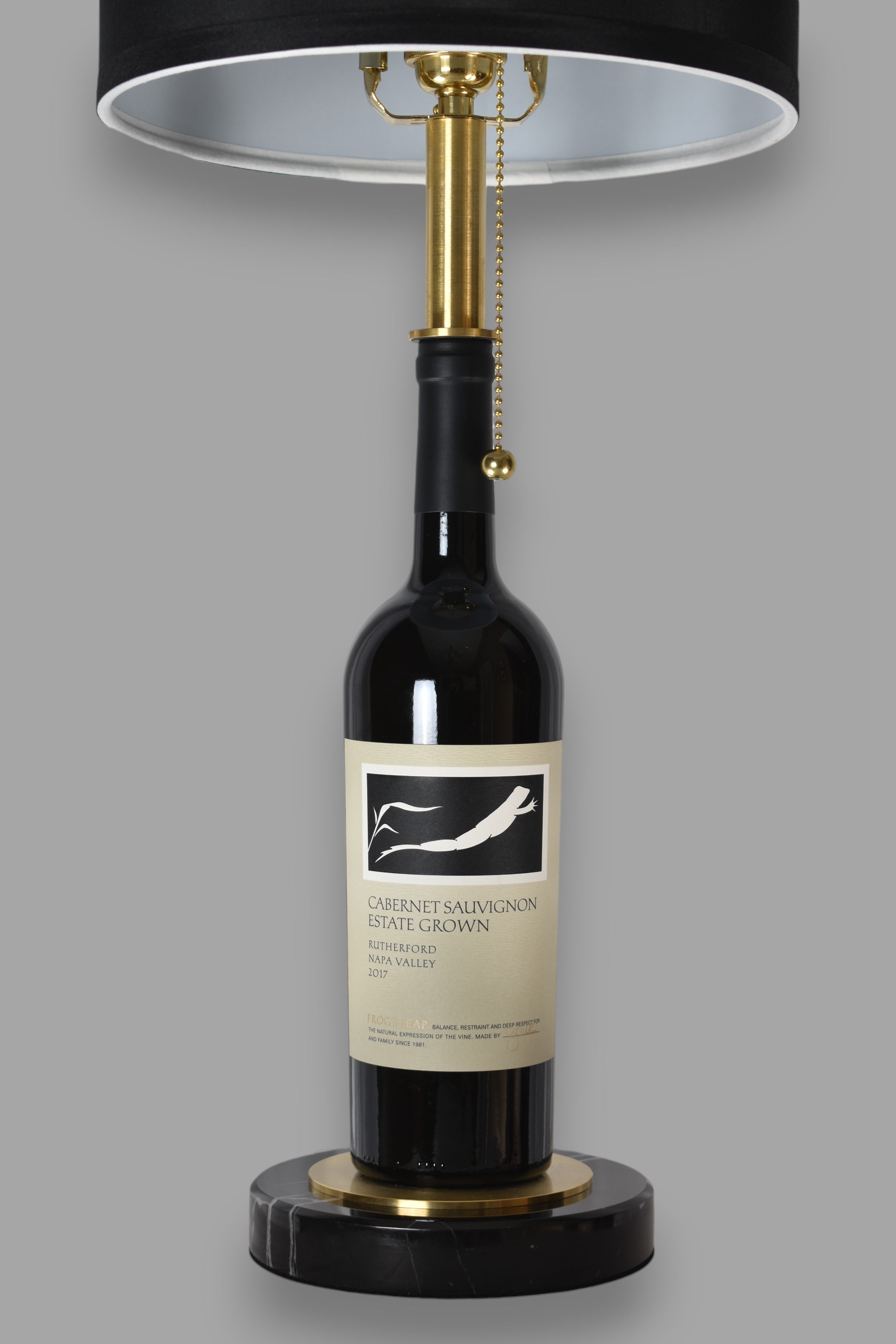 Wine bottle lamp made from a reclaimed 2017 Frog's Leap Cabernet Sauvignon bottle, front view, on a gray background