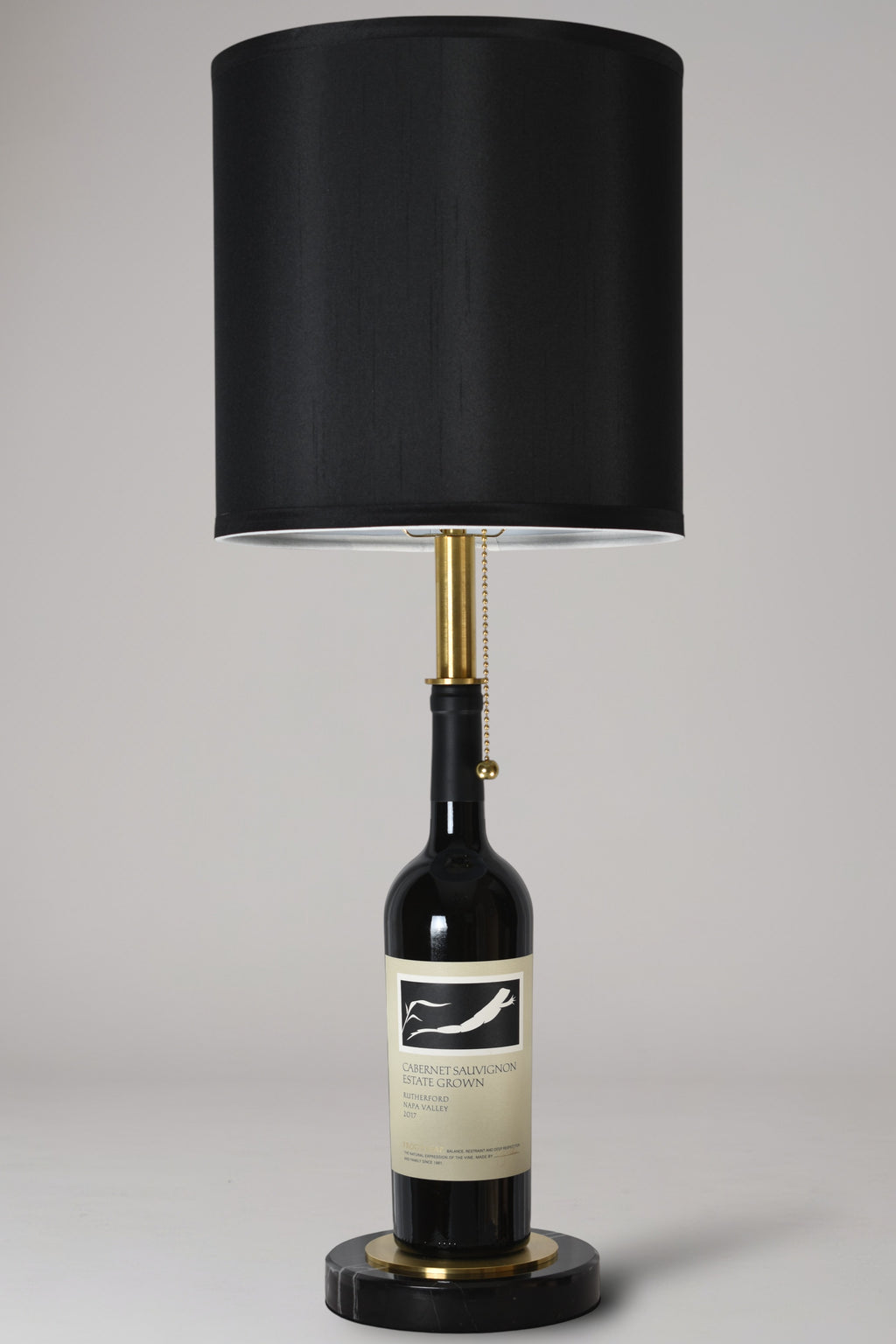 Wine bottle lamp made from a reclaimed 2017 Frog's Leap Cabernet Sauvignon bottle, full view, light off, on a gray background