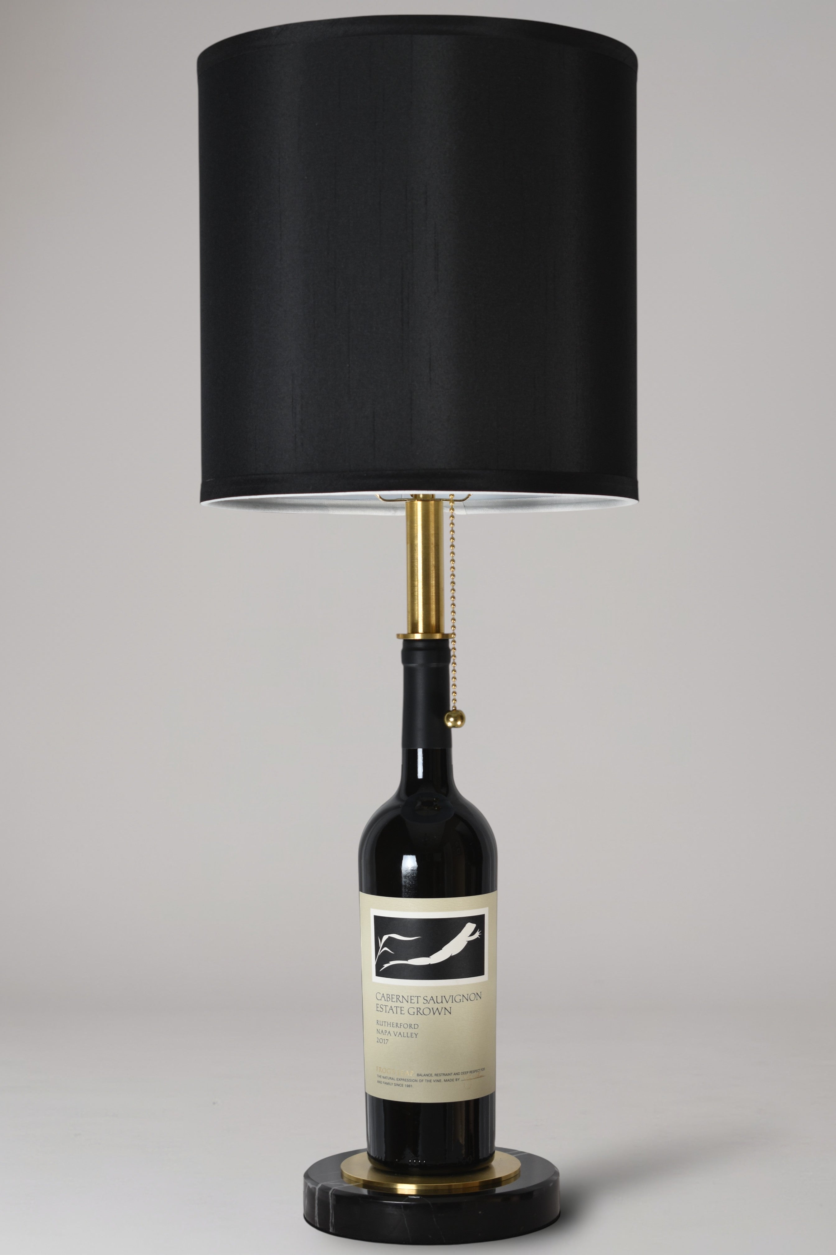Wine bottle lamp made from a reclaimed 2017 Frog's Leap Cabernet Sauvignon bottle, full view, light off, on a gray background