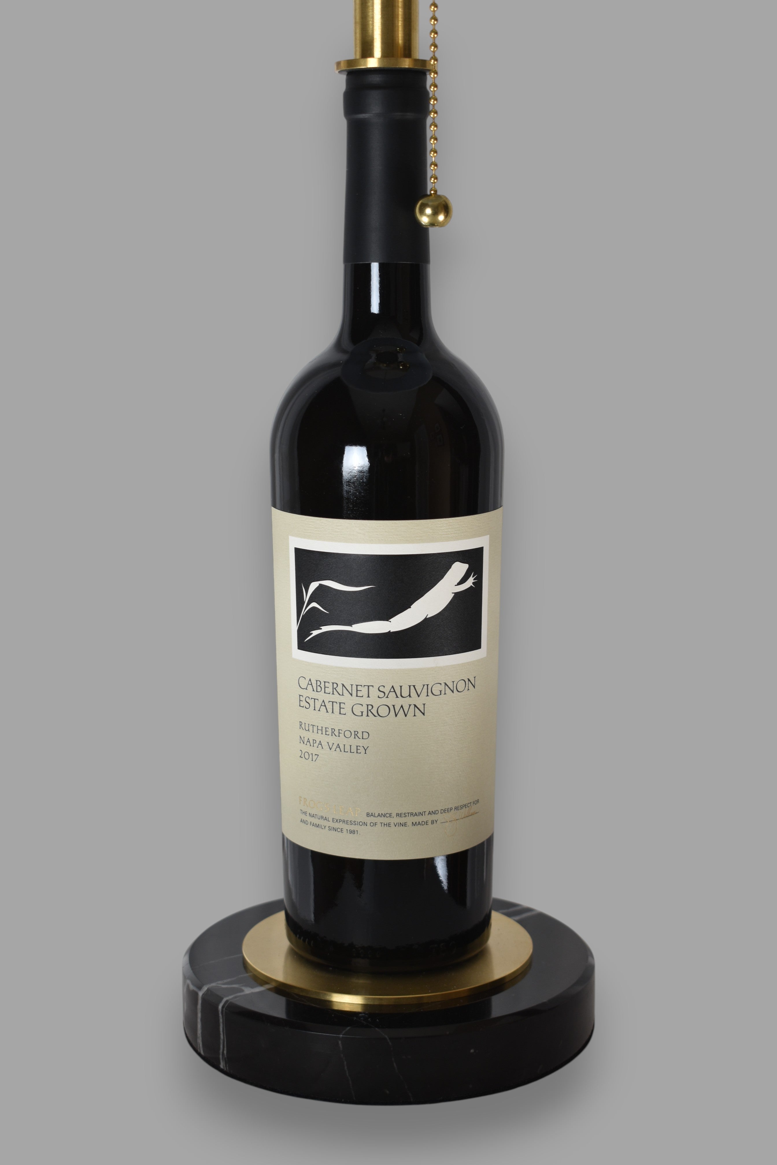Wine bottle lamp made from a reclaimed 2017 Frog's Leap Cabernet Sauvignon bottle, close-up view, on a gray background
