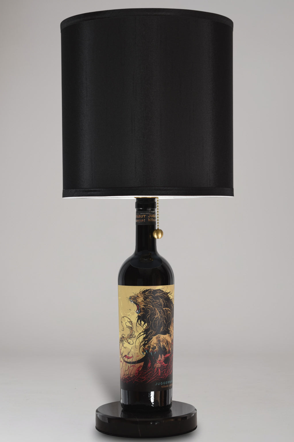 Wine bottle lamp made from a reclaimed Juggernaut Cabernet Sauvignon bottle, full view, light off, on a gray background