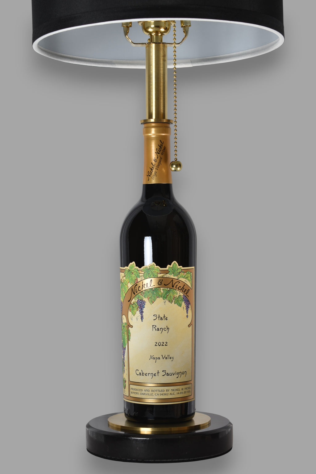 Wine bottle lamp made from a reclaimed 2022 Nickel & Nickel Cabernet Sauvignon bottle, front view, on a gray background