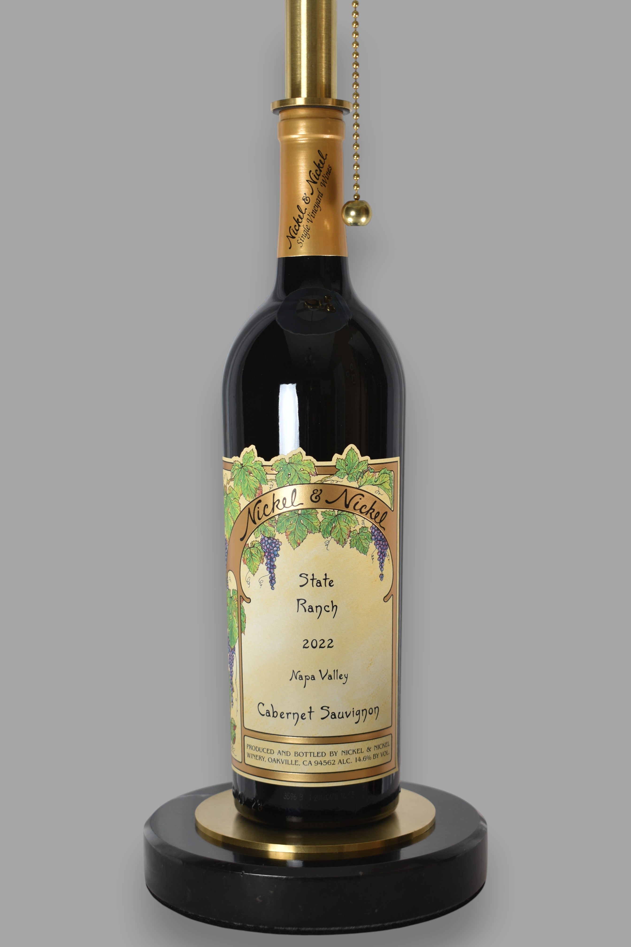 Wine bottle lamp made from a reclaimed 2022 Nickel & Nickel Cabernet Sauvignon bottle, close-up view, on a gray background