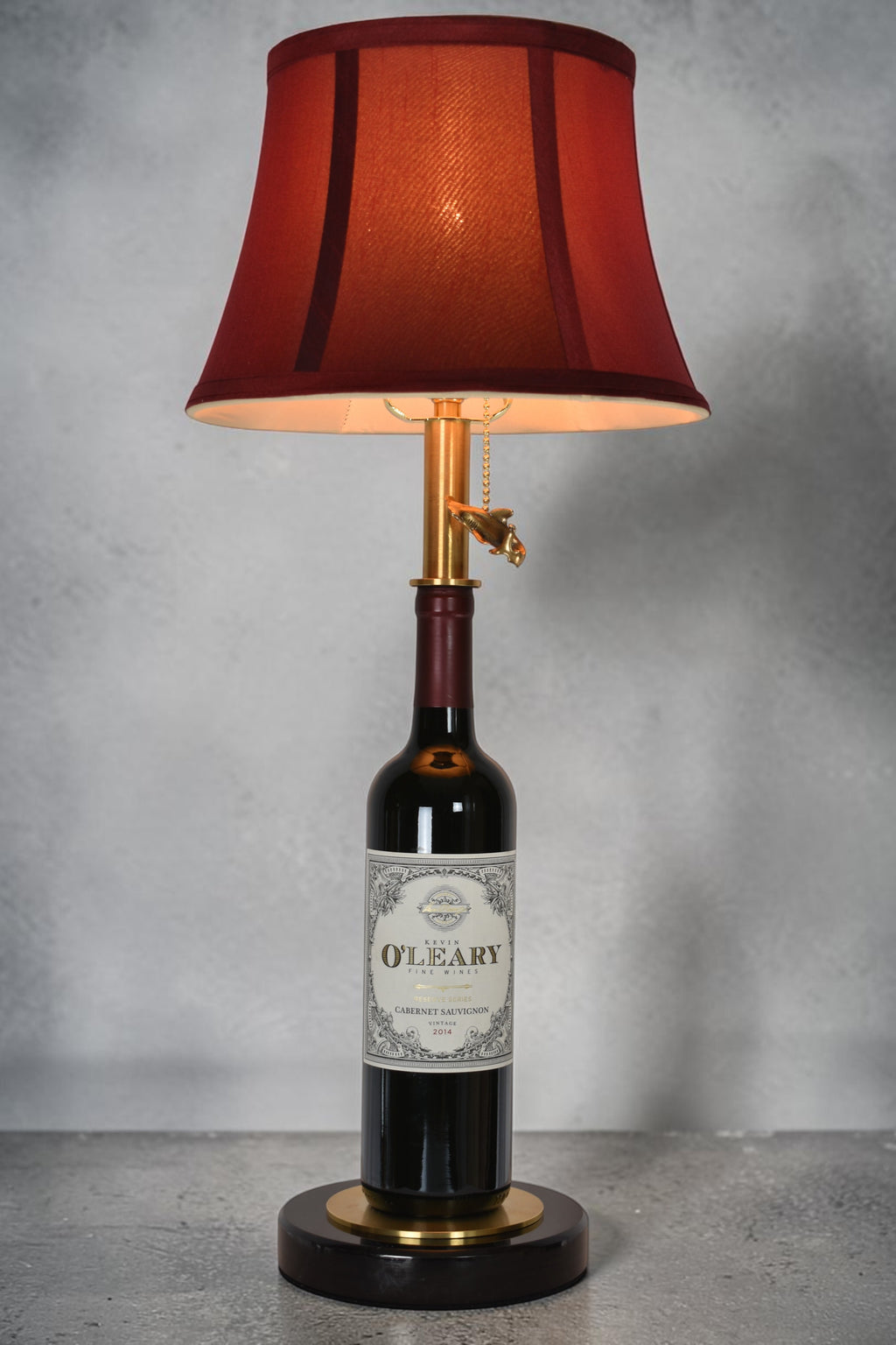 Wine bottle lamp made from a reclaimed 2014 O'Leary Cabernet Sauvignon bottle, full view, light on, on a gray background