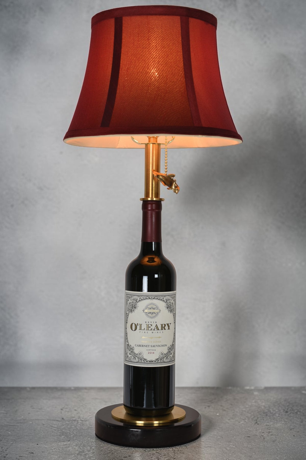 Wine bottle lamp made from a reclaimed 2014 O'Leary Cabernet Sauvignon bottle, full view, light on, on a gray background