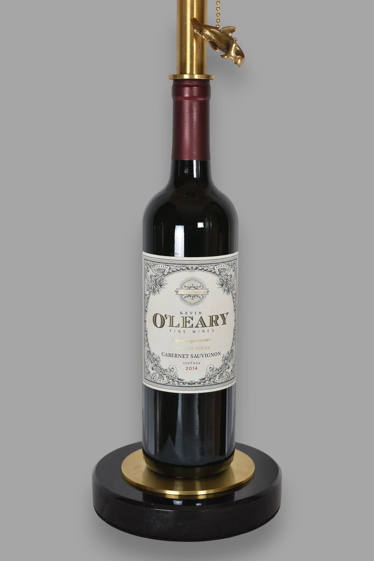 Wine bottle lamp made from a reclaimed 2014 O'Leary Cabernet Sauvignon bottle, close-up view, on a gray background