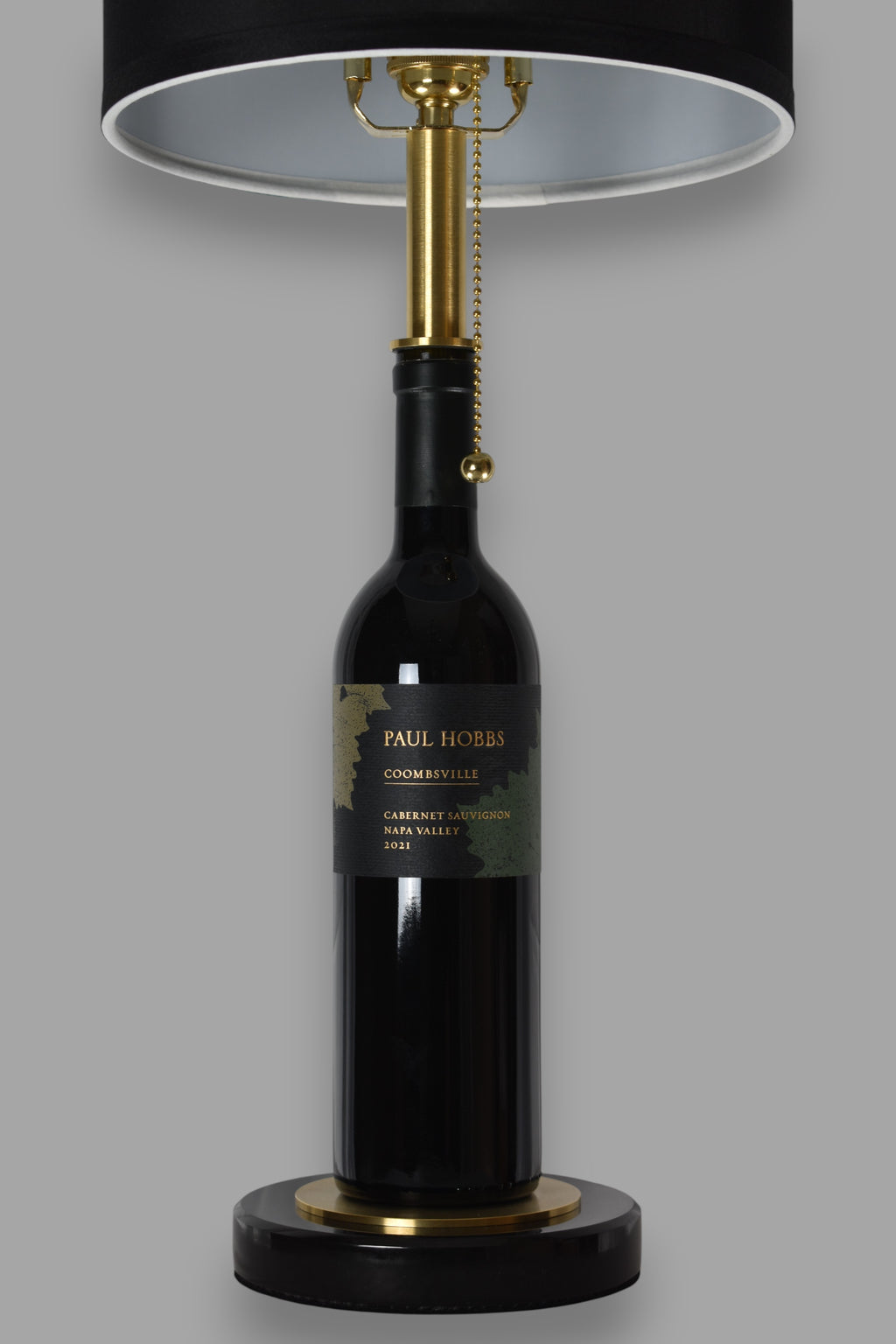 Wine bottle lamp made from a reclaimed 2021 Paul Hobbs Cabernet Sauvignon bottle, front view, on a gray background