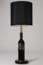 Wine bottle lamp made from a reclaimed 2021 Paul Hobbs Cabernet Sauvignon bottle, full view, light off, on a gray background