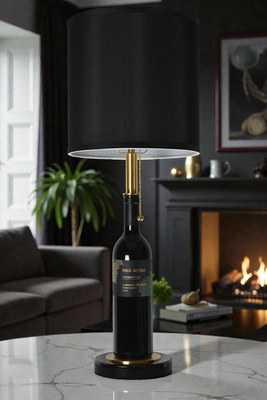 Wine bottle lamp made from a reclaimed 2021 Paul Hobbs Cabernet Sauvignon bottle, full view, light off, in a cozy living room