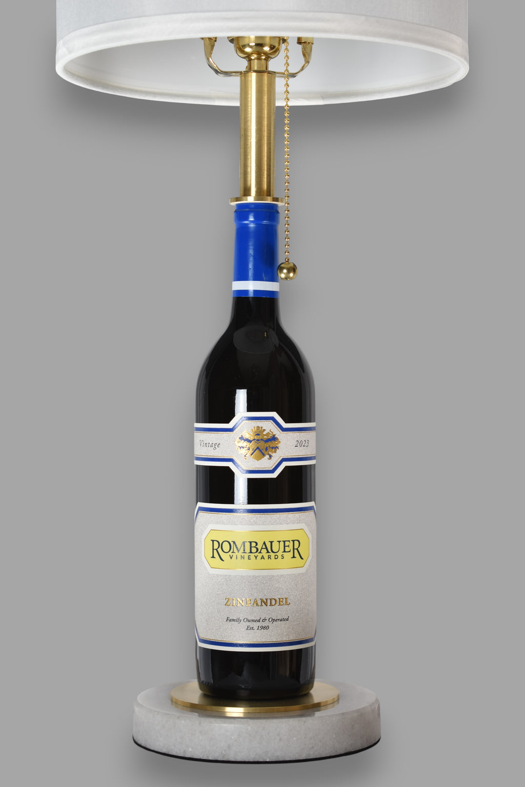 Wine bottle lamp made from a reclaimed 2023 Rombauer Zinfandel bottle, front view, on a gray background