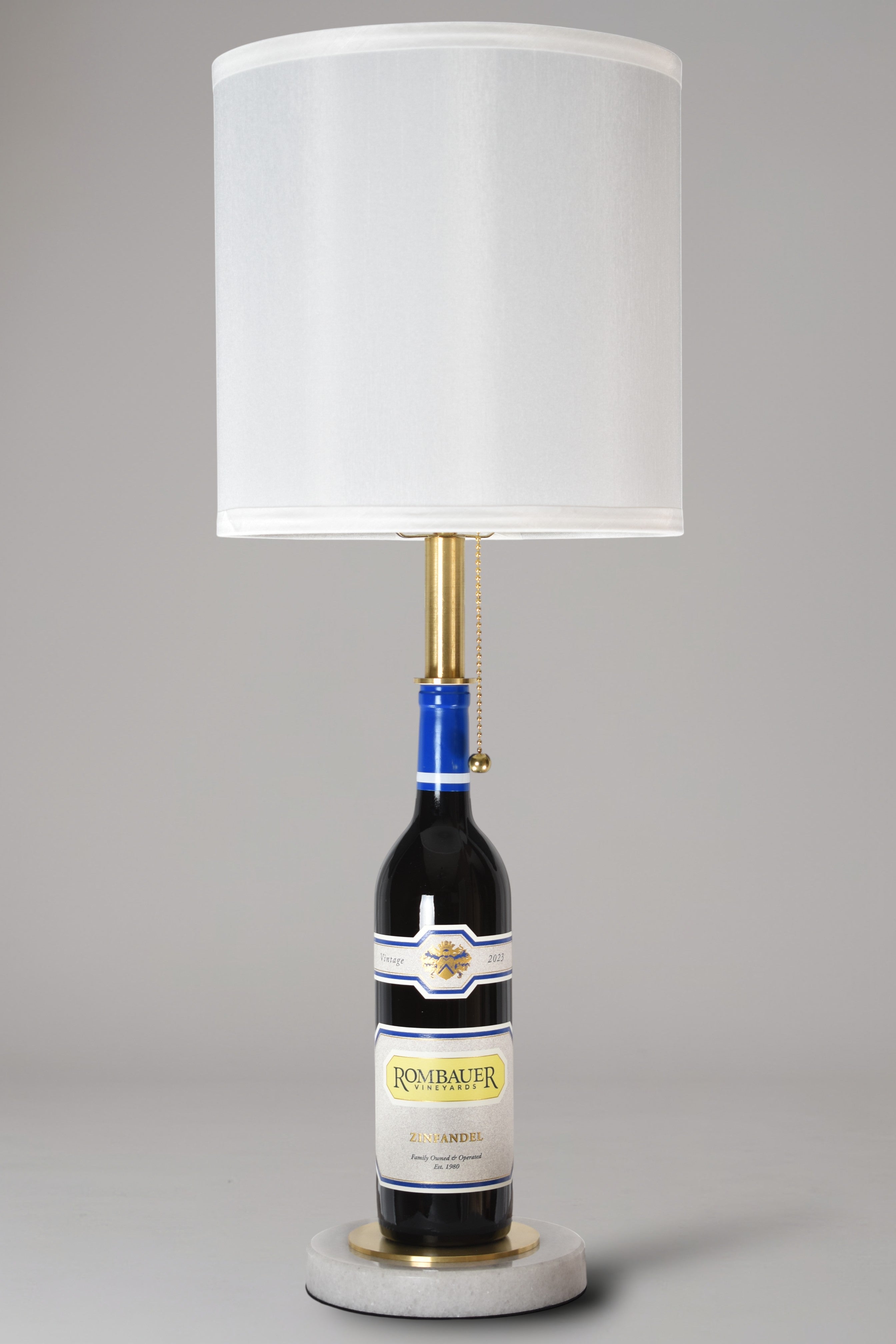 Wine bottle lamp made from a reclaimed 2023 Rombauer Zinfandel bottle, full view, light off, on a gray background