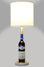 Wine bottle lamp made from a reclaimed 2023 Rombauer Zinfandel bottle, full view, light on, on a gray background