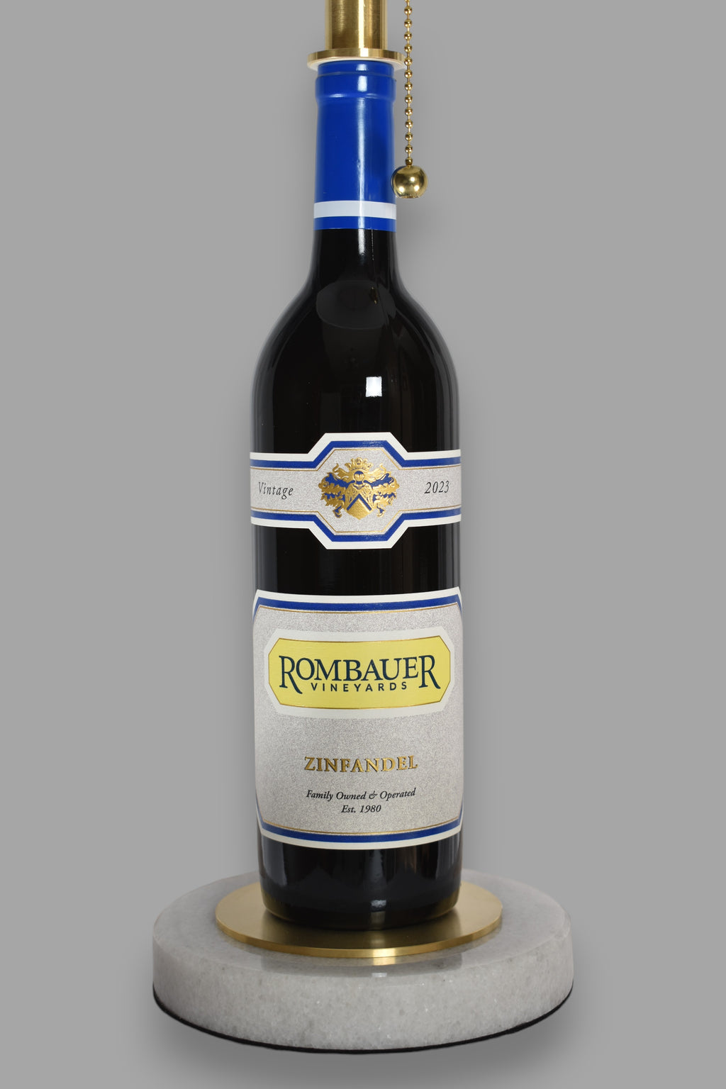 Wine bottle lamp made from a reclaimed 2023 Rombauer Zinfandel bottle, close-up view, on a gray background