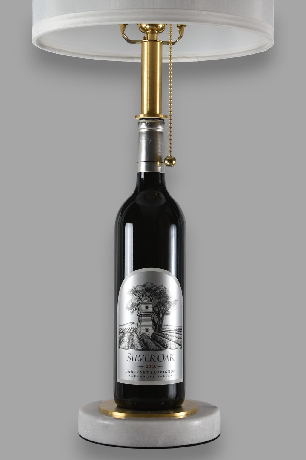 Wine bottle lamp made from a reclaimed 2020 Silver Oak Cabernet Sauvignon bottle, front view, on a gray background