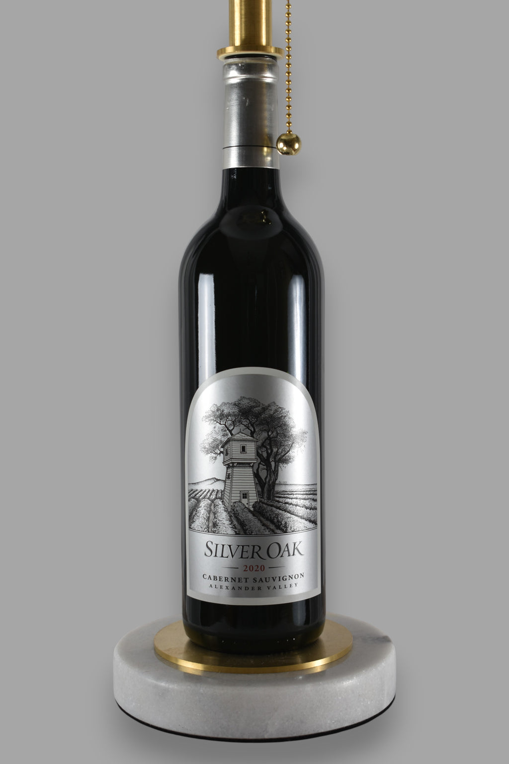 Wine bottle lamp made from a reclaimed 2020 Silver Oak Cabernet Sauvignon bottle, close-up view, on a gray background
