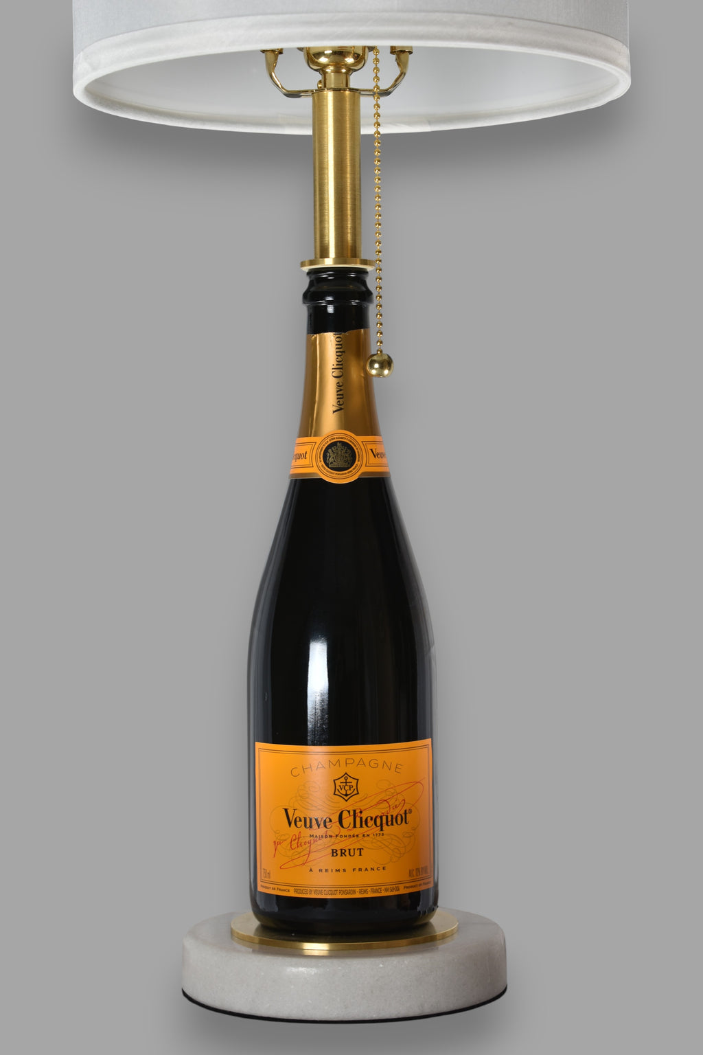 Wine bottle lamp made from a reclaimed Veuve Clicquot Brut Champagne bottle, front view, on a gray background