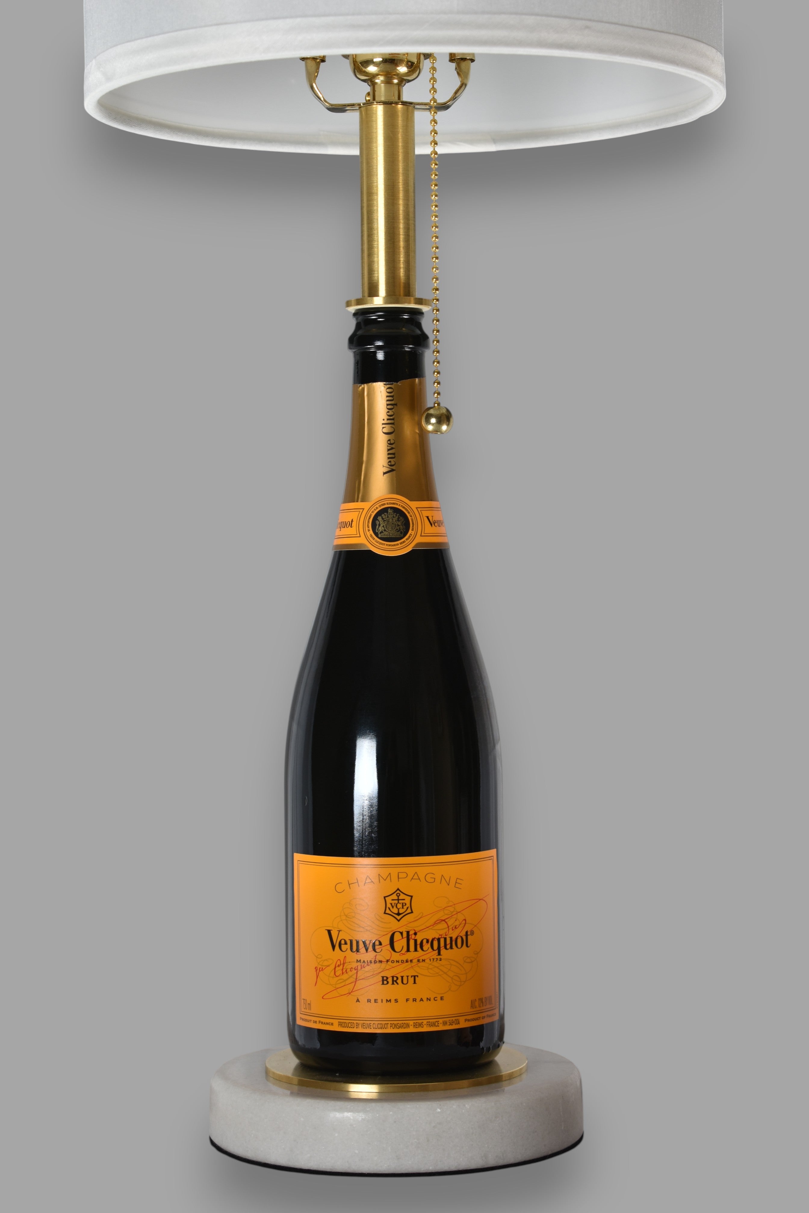 Wine bottle lamp made from a reclaimed Veuve Clicquot Brut Champagne bottle, front view, on a gray background