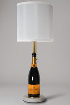 Wine bottle lamp made from a reclaimed Veuve Clicquot Brut Champagne bottle, full view, light off, on a gray background